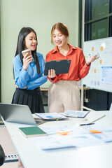 Two young female business consultants work on startup, collaborating on mobile app development social media strategies. whiteboards, documents, they aim to build a successful e-commerce business.