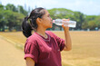© M Alfan Setyawan - asian woman drink a bottle of water after running in outdoors in midday wearing casual t shirt
