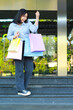 © M Alfan Setyawan - vertical shoot of smiling asian woman holding shopping bag walking in stairway in front of city mall entrance