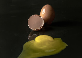 View of Broken egg yolk with Broken raw chicken eggshell in front of Fresh chicken egg (Hen eggs) on Dark background. Fresh eggs from the farmer, Natural organic healthy food concept, Space for text, 