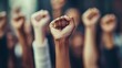© danadesa - Diverse group of people raising their fists in the air during a protest, representing unity, strength, and solidarity.