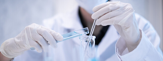 close-up scientist pouring blue liquid into test tube beaker flask equipment pipette working laborat