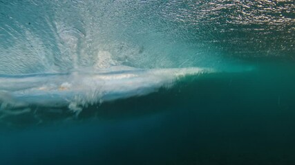 Wall Mural - Young man swims in the ocean with waves. Man dives underwater under the breaking ocean wave on sunrise. Person swims in the crushing waves