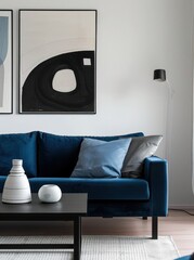 A blue velvet sofa with two throw pillows sits in front of a black coffee table with two decorative objects Two abstract art pieces are hanging on the wall behind the sofa