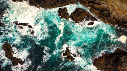  Stunning Aerial View of Vibrant Turquoise Waves Elegantly Crashing Against Rocky Shoreline