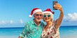© Oksana - Senior couple wearing santa hats taking selfie on tropical beach