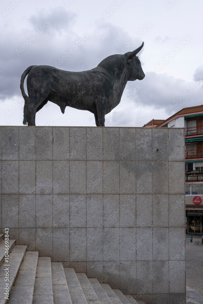 Bullfighting Building Madrid, Madrid - April 02, 2024: Bronze statue of a bull on a cloudy ...
