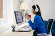 © PaeGAG - Businesswoman wearing headphones and working from home is taking a coffee break while looking at her computer screen displaying charts