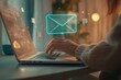 © gankevstock - Person typing on laptop with holographic email icons in home office