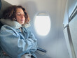 © Юлия Завалишина - Rest on plane. Young woman napping sitting by porthole in business jet using neck pillow for travel. Passenger girl flying in plane. Girl sleeping in airplane going on trip vacation. Traveling girl