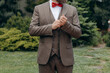 © Alex - A man with  in a stylish suit  fixes a bow tie. Morning of the groom. Bride helps to fix the groom jacket and accessories