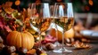 © Hryhor Denys - Two elegant wine glasses filled with white wine sit on a rustic wooden table adorned with vibrant autumn leaves, pumpkins, and seasonal decorations for Thanksgiving