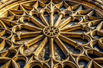 A beautifully intricate stone rose window featuring a geometric pattern, showcasing craftsmanship and medieval architectural design elements.