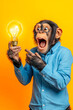 © sergign - A chimpanzee in a blue shirt holds a glowing lightbulb, its expression of surprise and excitement highlighting the concept of ideas and inspiration.