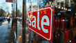 © olenap - Picture of shop at fashion store window display with text SALE on red poster in the shopping mall. Sale concept Sale sign in a shop window and people in street in background AI