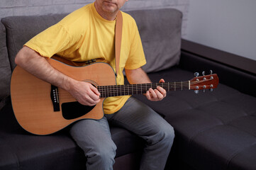 Man paying a acoustic guitar in office. Male musician playing music instrument