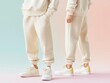 © WE.ARE.AI - Front and back view of blank beige sweatpants with soft fabric folds, placed on a pastel gradient background, Sweatpants, Casual fashion 3D mockup