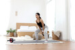© Stella - Asian woman using kettlebell for exercise on yoga mat in bedroom. Happy female lifting kettlebell weight for work out at home. Sporty girl doing exercise in front of bed. Healthy and sport hobby