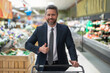 © Volodymyr - Businessman in a suit shopping in the supermarket. The businessman with shopping cart selecting fresh groceries. The man pushes his shopping cart down the aisles. Manager shopping in the grocery store
