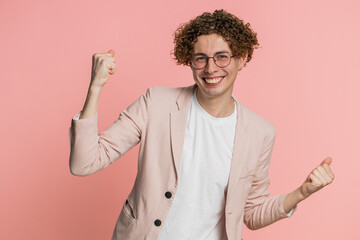 Happy joyful Caucasian man celebrating success victory, winning birthday, lottery jackpot goal achievement play game good positive news triumph. Young handsome guy isolated on pink studio background