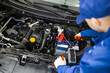 © zphoto83 - A mechanic is working on a car's battery in a garage