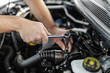 © zphoto83 - A mechanic repairs an engine using a ratchet wrench in a car at a workshop during the daytime