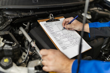 Wall Mural - Mechanic conducting a vehicle inspection with a clipboard in a workshop environment during daylight