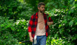 © Volodymyr - The Lumberjack holds axe with serious face on the forest. A lumberjack with a large ax examines the tree before felling. Serious lumberjack. Confident young bearded man holding a big axe outdoor.