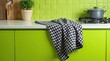 © Cloudy - A black-and-white checkered kitchen towel is draped over a vivid lime green counter, with the contrasting colors creating a lively and stylish kitchen setting.