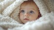 © garpinina - blue eyed newborn baby peeking from a soft, cozy white blanket
