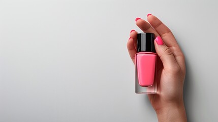 Female hand holding pink nail polish bottle on neutral background. Minimalist beauty product display with elegant and modern style. Top view photography with copy space for banner.

