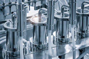 Poster - A series of silver containers with a bright light shining on them. Scene is industrial and mechanical