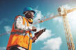 © peopleimages.com - Engineering, construction site and black man with tablet, smile and blue sky with architecture. African person, employee or inspector with tech, digital app or check for regulations, hard hat or joy