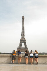  Tourists, a group of friends standing on a bridge in Paris, the capital of France, looking at the Eiffel Tower. Photography, tourism concept, tour of Europe.