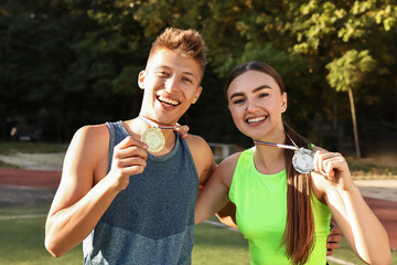 Two happy winners with medals at stadium