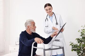 Doctor consulting senior patient with walking frame in hospital ward