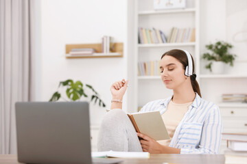 Wall Mural - Student in headphones holding notebook and studying indoors