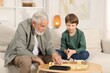 © New Africa - Grandpa and his grandson playing dominoes at table indoors