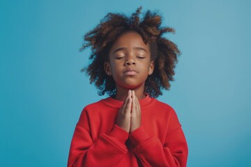 A young girl with her eyes closed in prayer, a moment of devotion and reflection