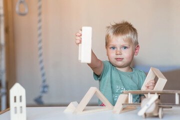 a little boy of 2 years old is playing a developing logistics constructor. children's wooden toys. m