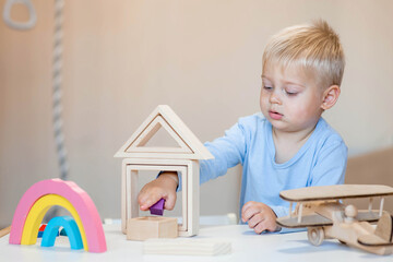 A little boy of 2 years old is playing a developing logistics constructor. Children's wooden toys. Montessori for child development.