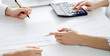 © rogerphoto - Accountant using a calculator and laptop computer for counting taxes with a client or a colleague at white desk in office. Teamwork in business audit and finance