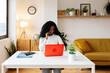 © Xavier Lorenzo - Successful happy young African American businesswoman talking on phone call while using her laptop at home office. Business people and multitasking concept