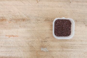 Meses chocolate 1. Chocolate Meses in a plastic container on a wooden background