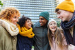 © Xavier Lorenzo - Young group of people having fun together outdoors in a winter day. Multiracial best friends in warm clothes enjoying time together at city street. United millennial students laughing.