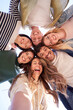 © CarlosBarquero - Vertical. Selfie portrait from below of diverse generation z group friends posing smiling in circle looking at camera outdoor. Happy multiracial young people having fun embracing together sunny day