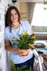 Wall Mural - Beautiful brunette woman houseplant growth hobby watering potted plant at home garden closeup. 