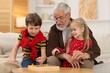 © New Africa - Grandpa and his grandkids playing with math game Times table tray at home