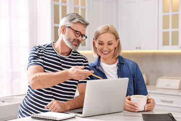 Wall Mural - Middle aged couple working at white marble table in kitchen