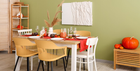 Poster - Autumn table setting with pumpkins, dry leaves and burning candles in dining room